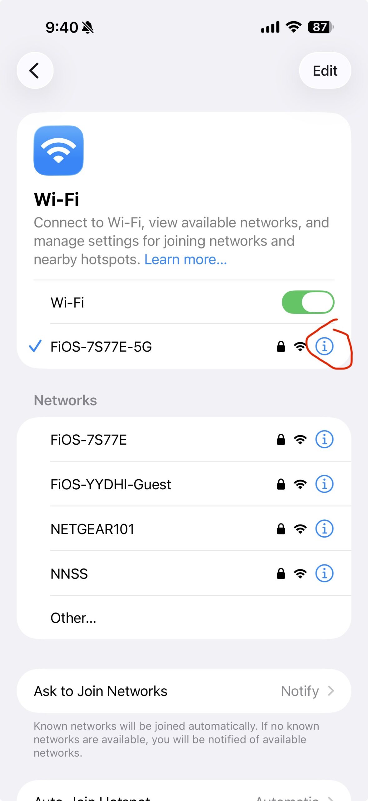 Screenshot of the iPhone Wi-Fi screen. A list of available networks is shown. The currently connected home network FiOS-7S77E-5G has a blue checkmark next to it. The blue circled lowercase letter i — the information icon — to the right of that network is circled in red. That is the button to tap.